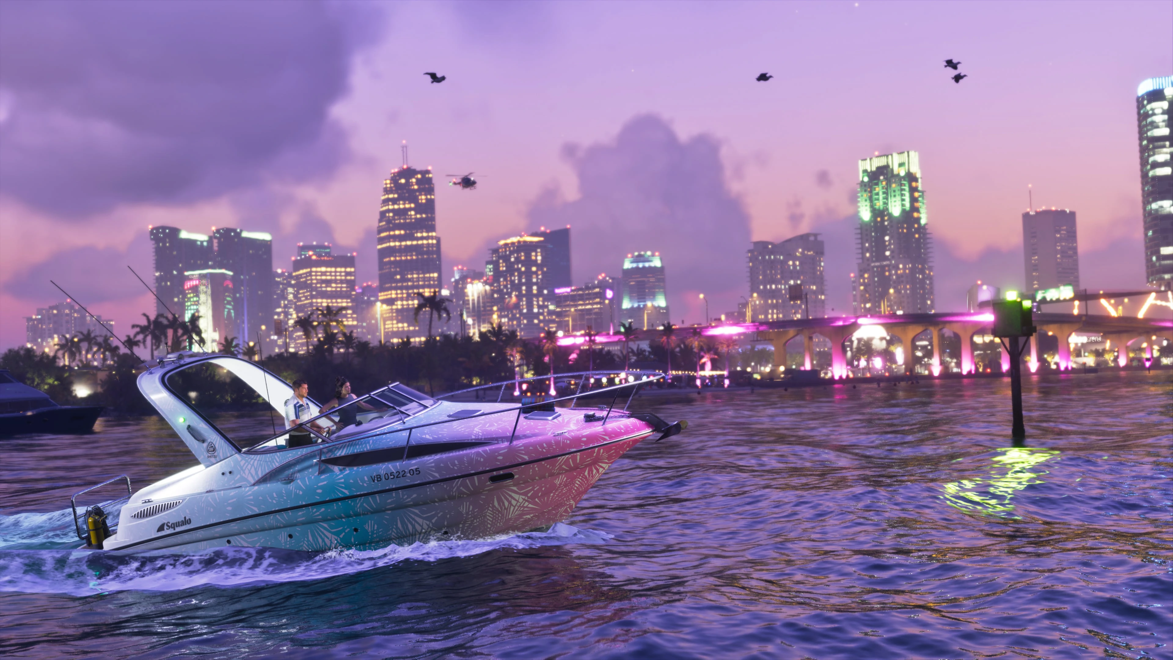 A gradient pink and blue Squalo moves through the water at night, with the illuminated city skyline in the background.