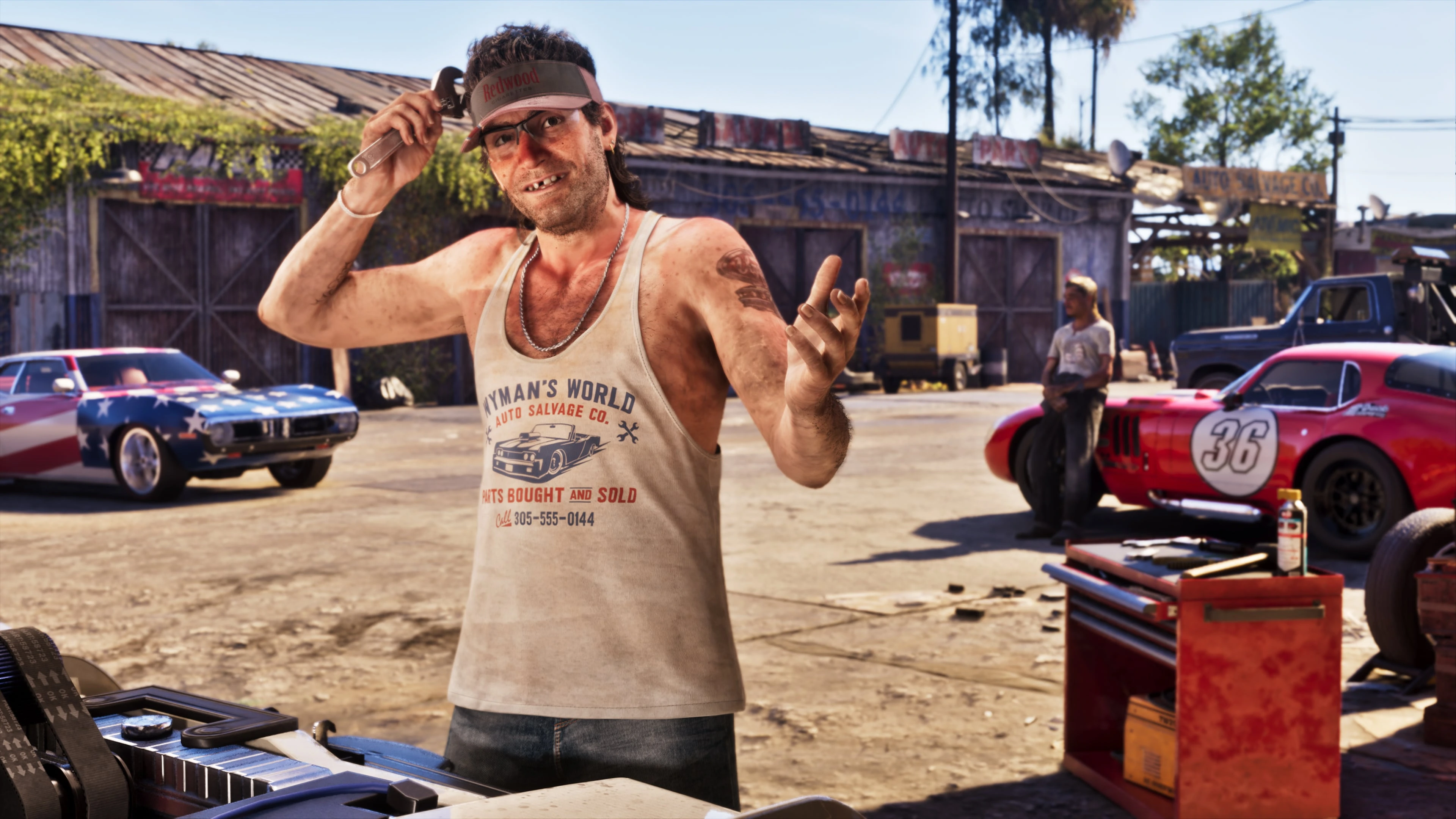 Wyman standing outside of a garage with a wrench in his right hand.